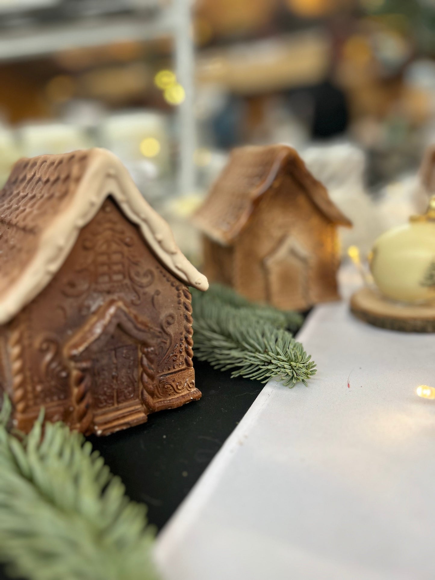 Bougie en forme de maison pain d’épices avec motifs sculptés et toit glacé, création artisanale