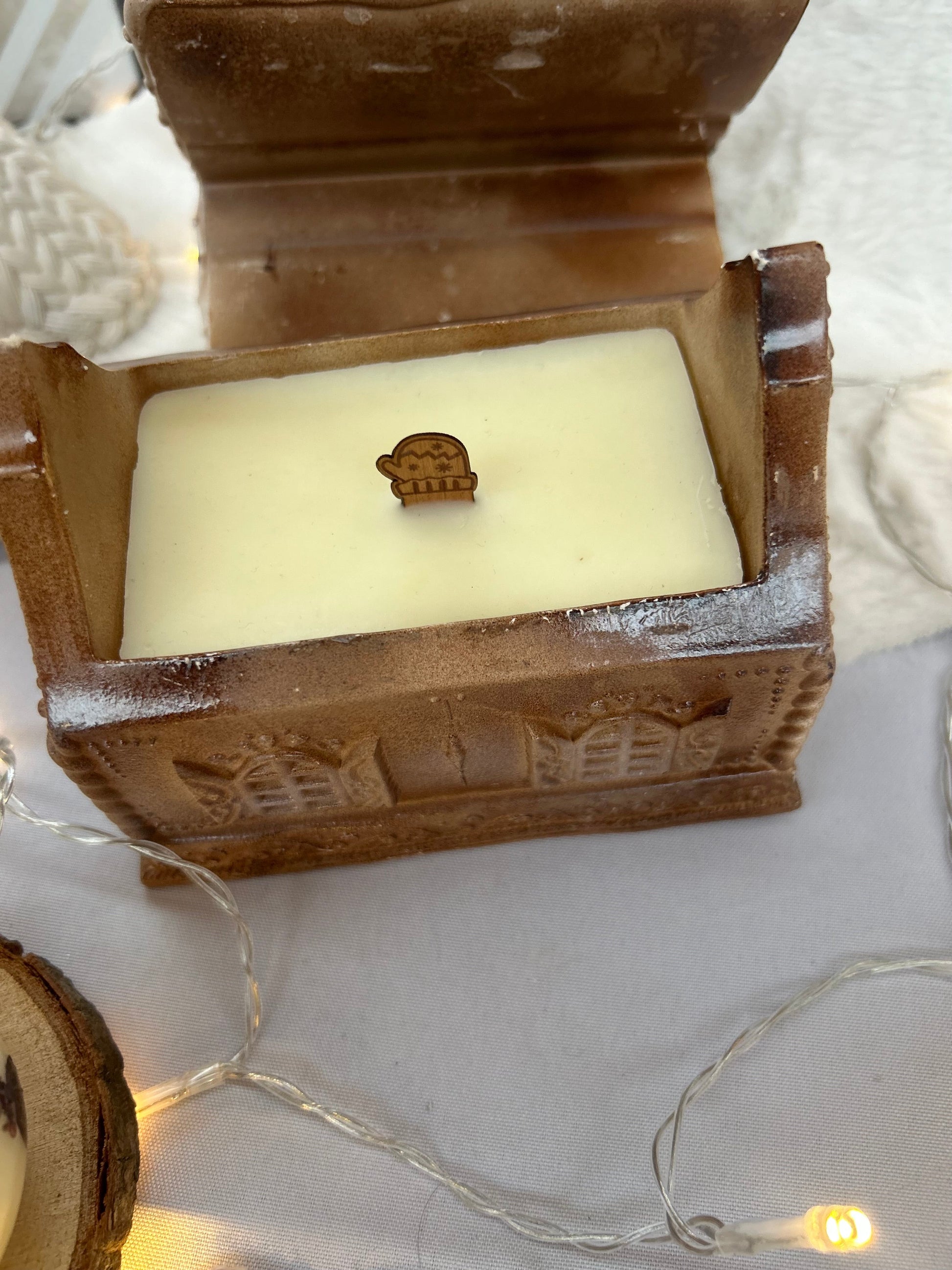 Bougie de Noël en forme de maison pain d’épices, finition artisanale chaleureuse.