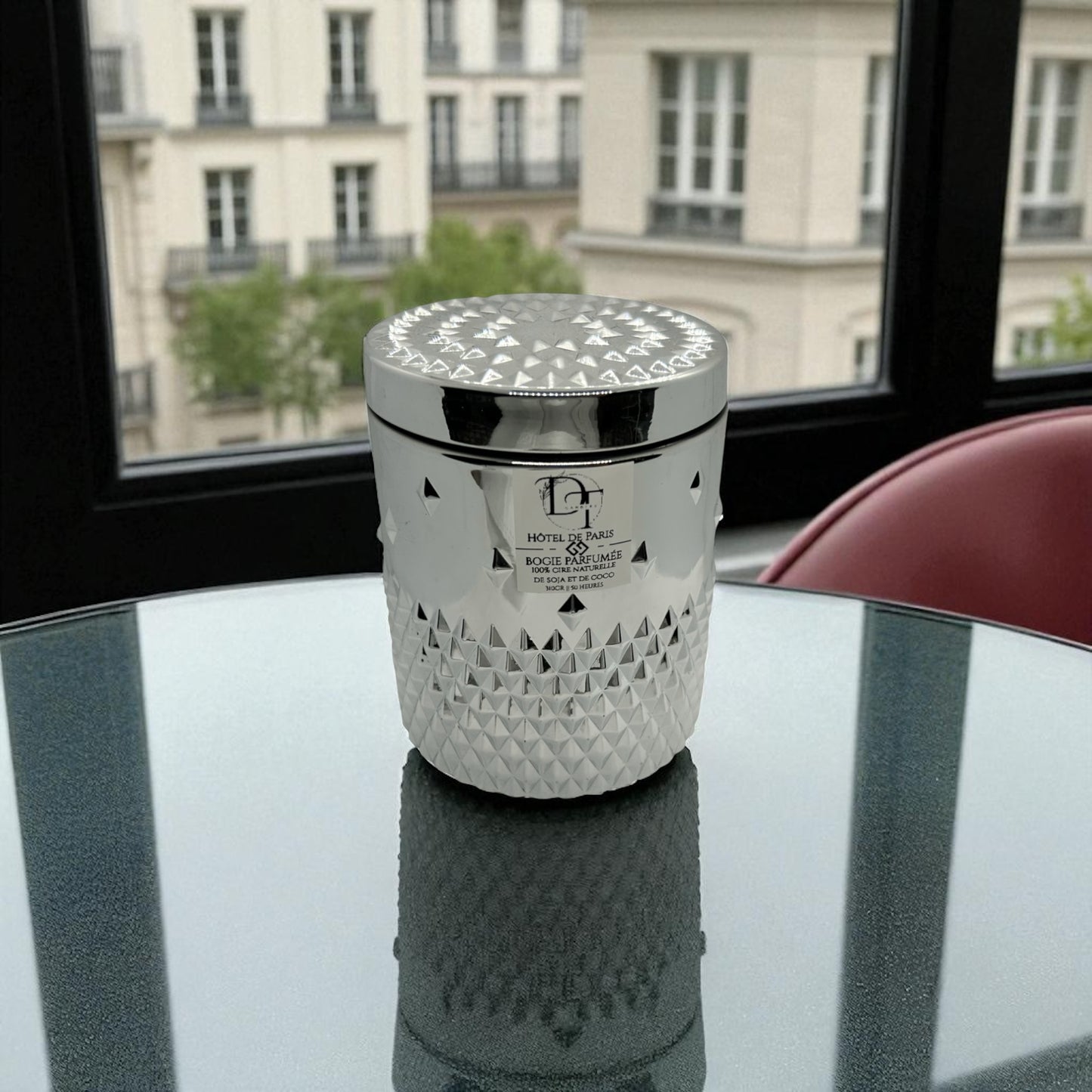 Decorative candle with geometric pattern on a reflective surface with a cityscape in the background