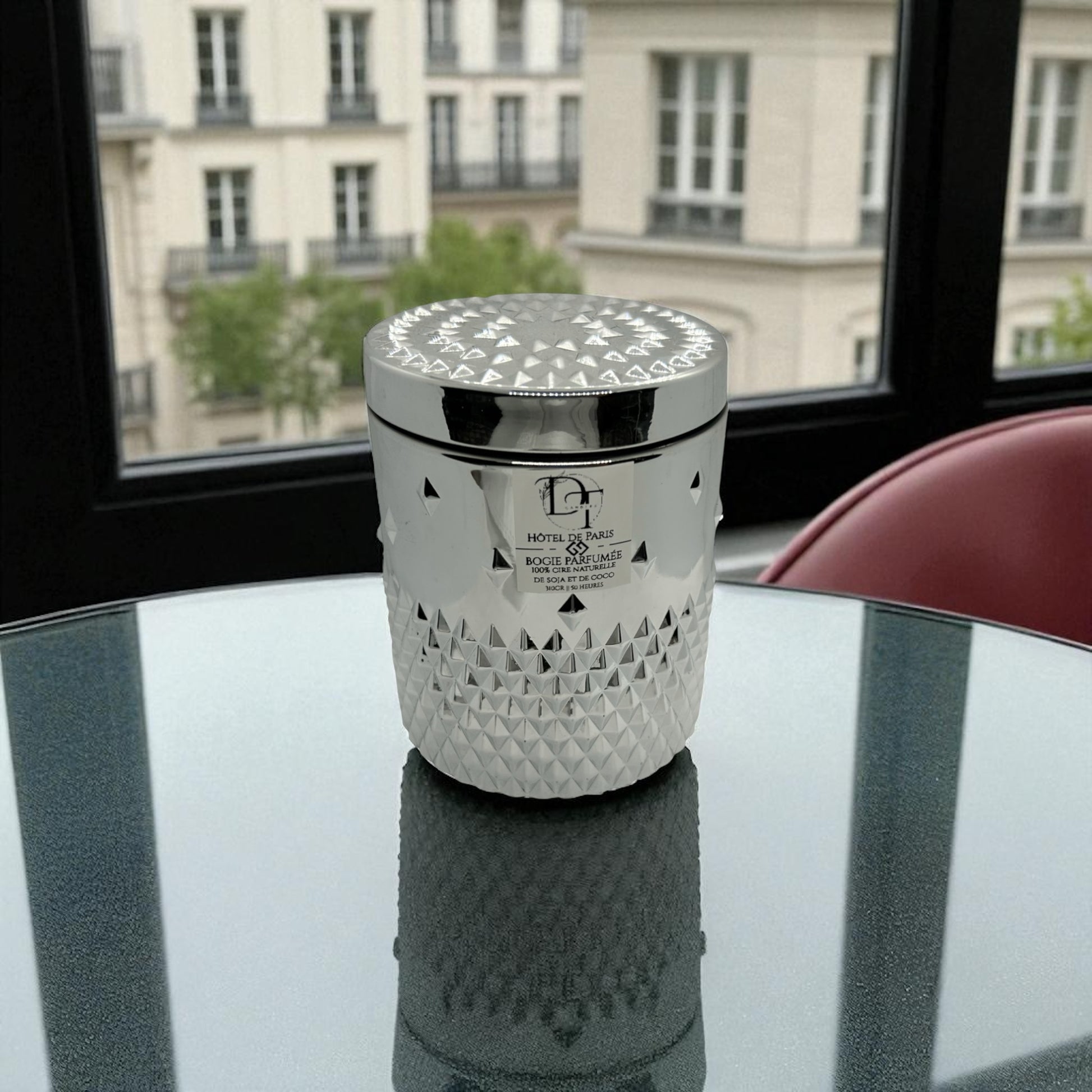 Decorative candle with geometric pattern on a reflective surface with a cityscape in the background