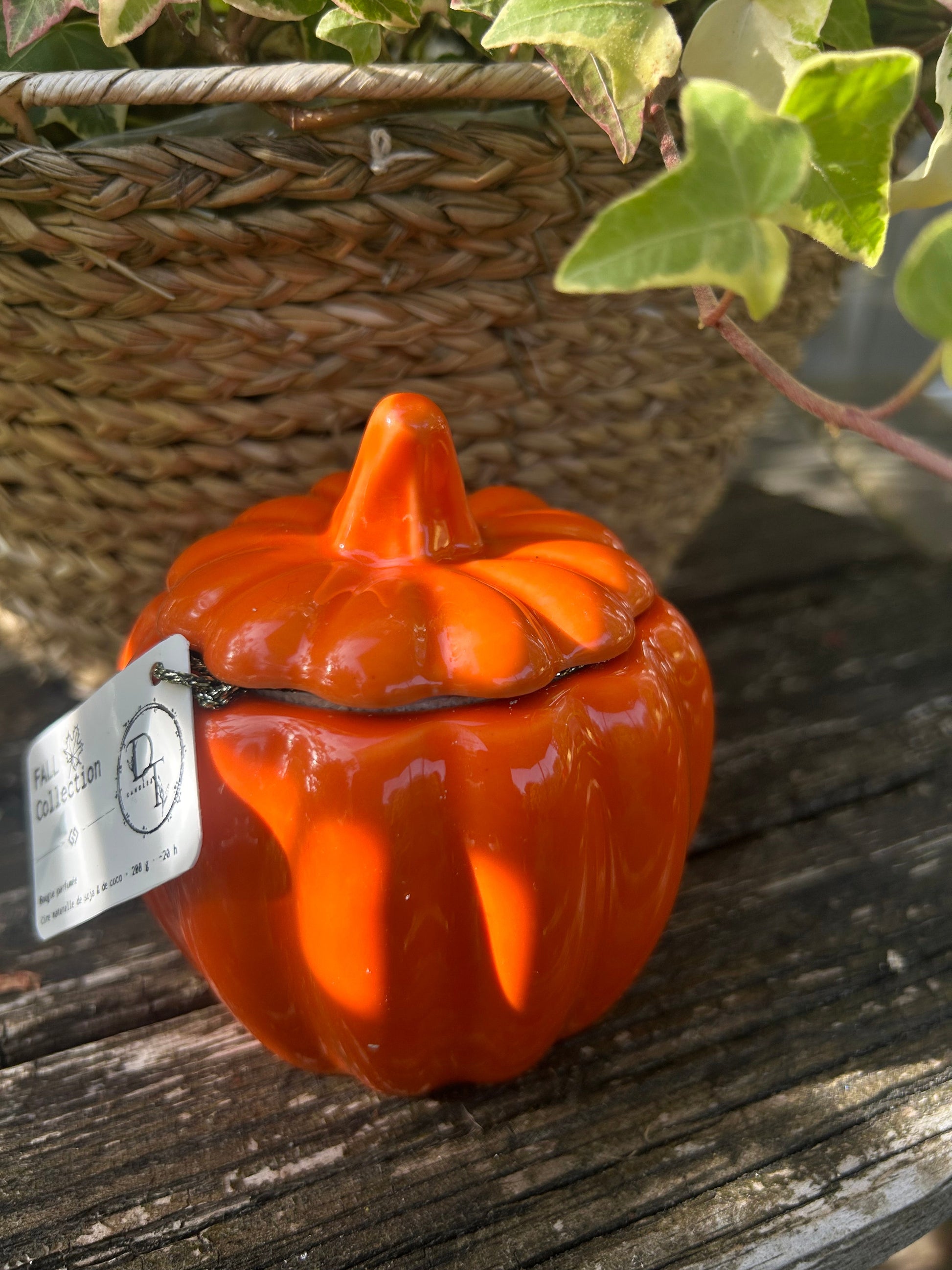 Orange ceramic pumpkin-shaped container with a tag on a wooden surface