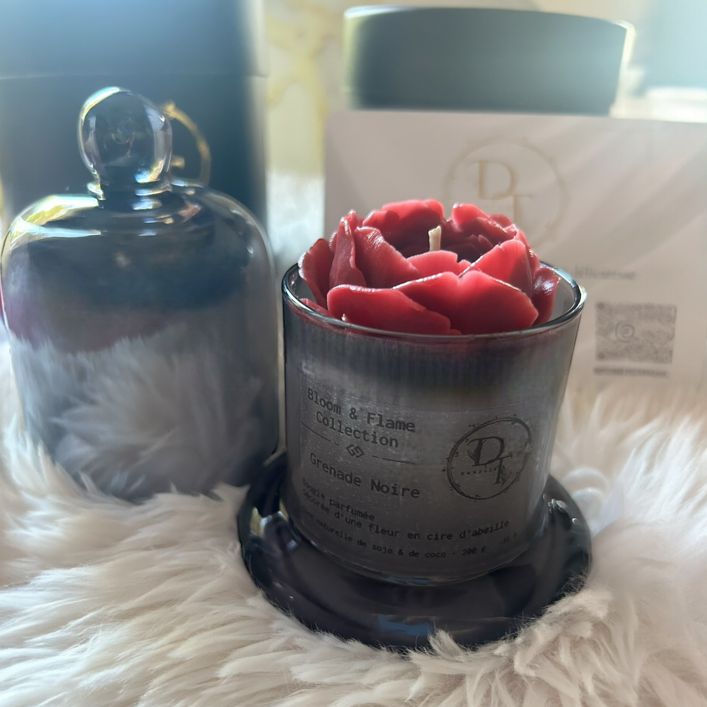 Red rose-shaped candle in a gray container on a fluffy white surface