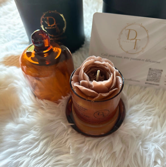Decorative candle shaped like a rose with an amber glass container on a white fluffy surface.