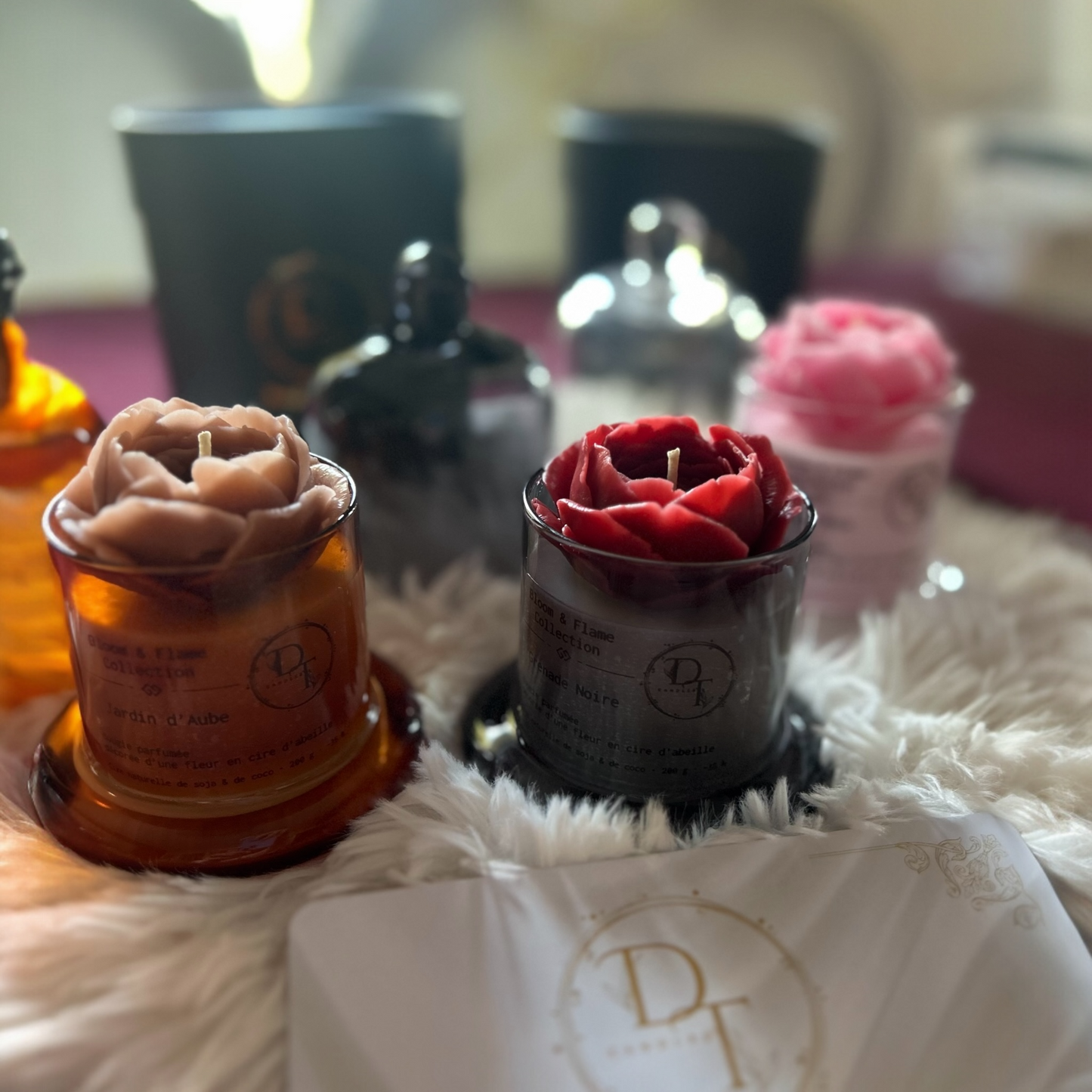 Decorative candles with rose shapes on a textured surface, featuring a brand logo.