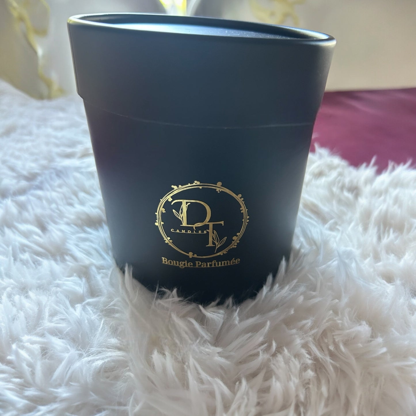 Black container with gold logo and text on a white fluffy surface