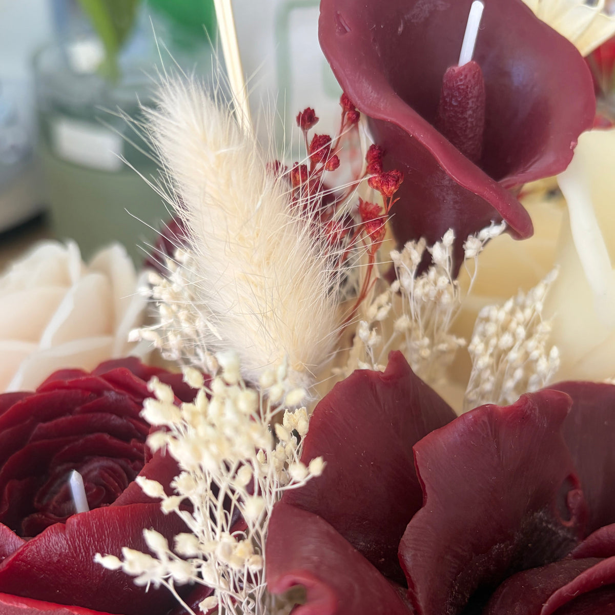 Détail d’un bouquet de fleurs en cire d’abeille bordeaux et ivoire, façonnées à la main