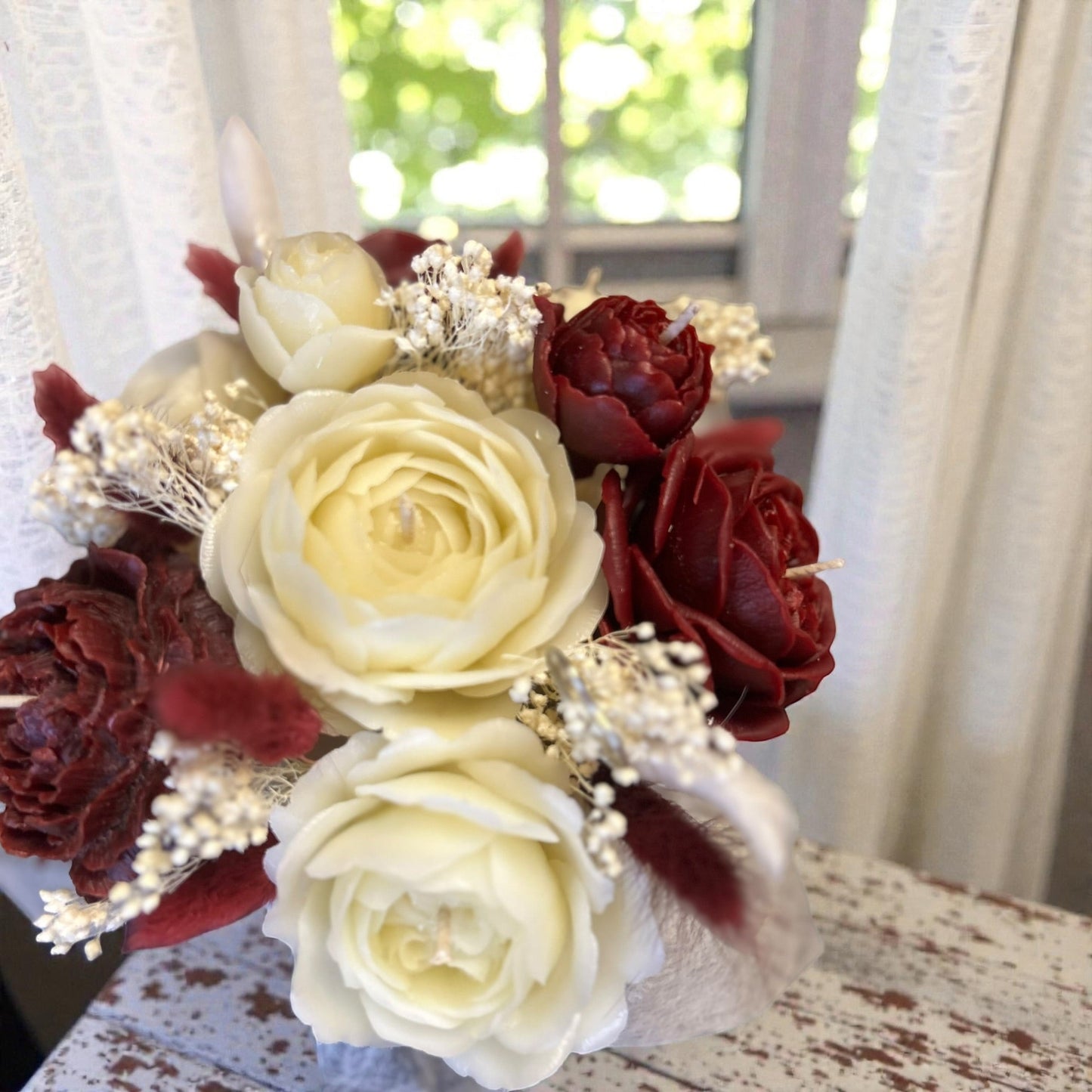 Détail de fleurs sculptées en cire d’abeille rouge et ivoire – bougie fleurie faite main
