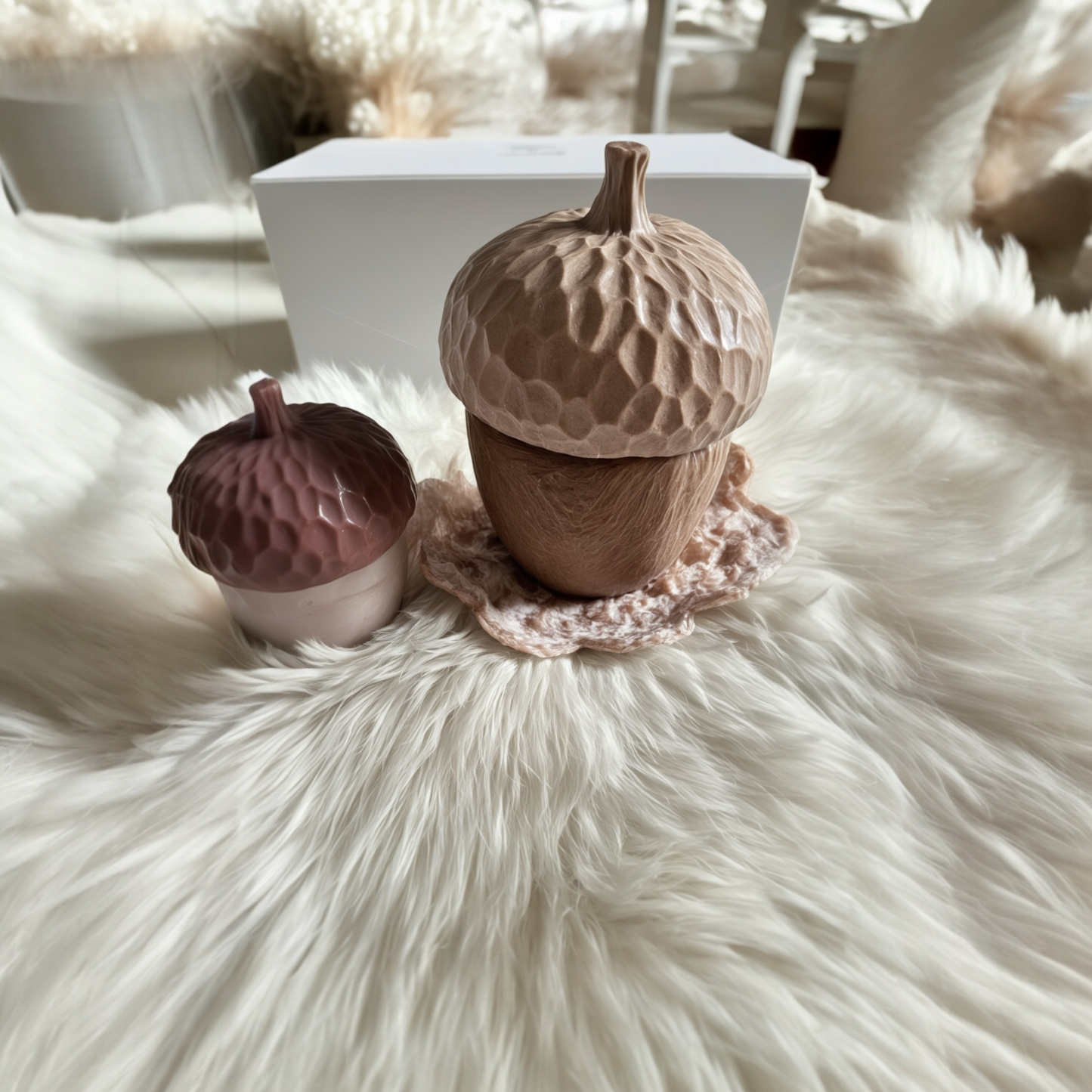 Two decorative acorn-shaped items on a fluffy white surface