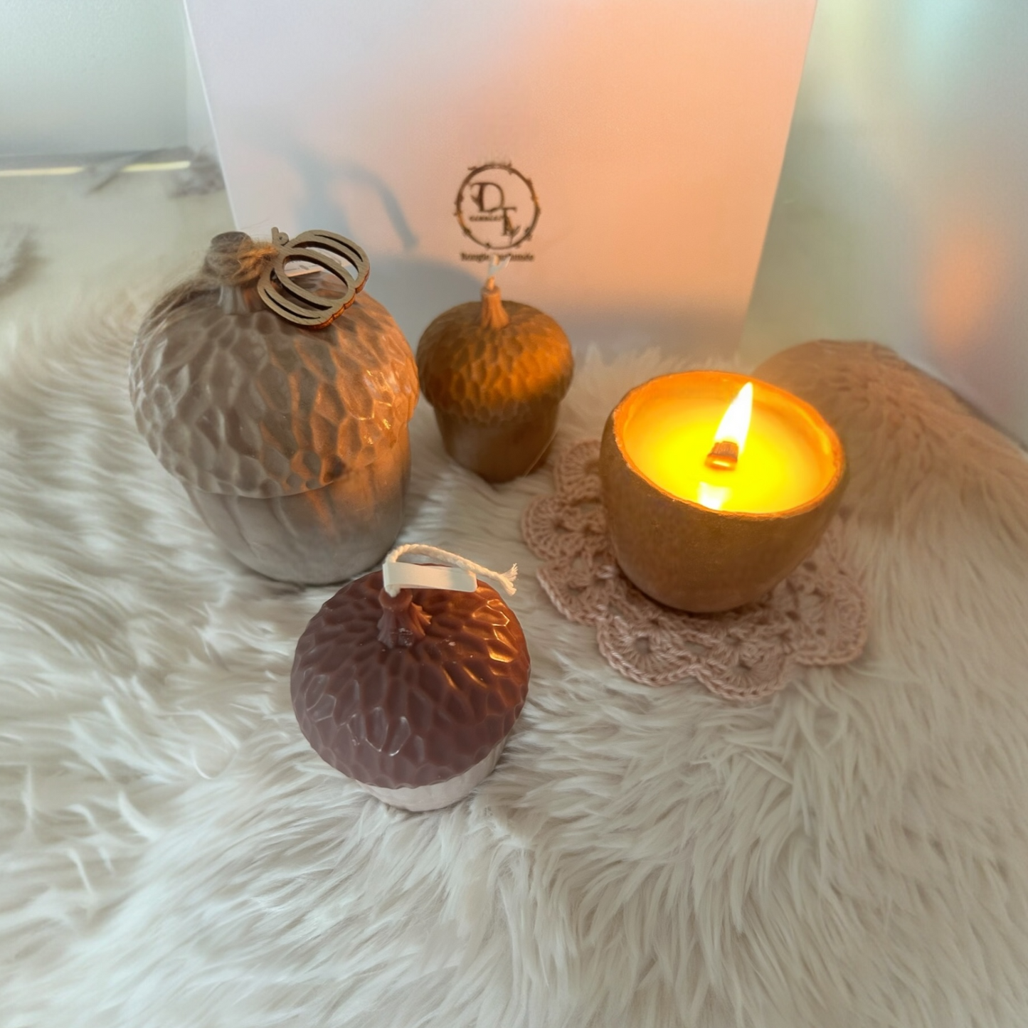 Decorative candles and a lit candle on a fluffy surface with a blurred background