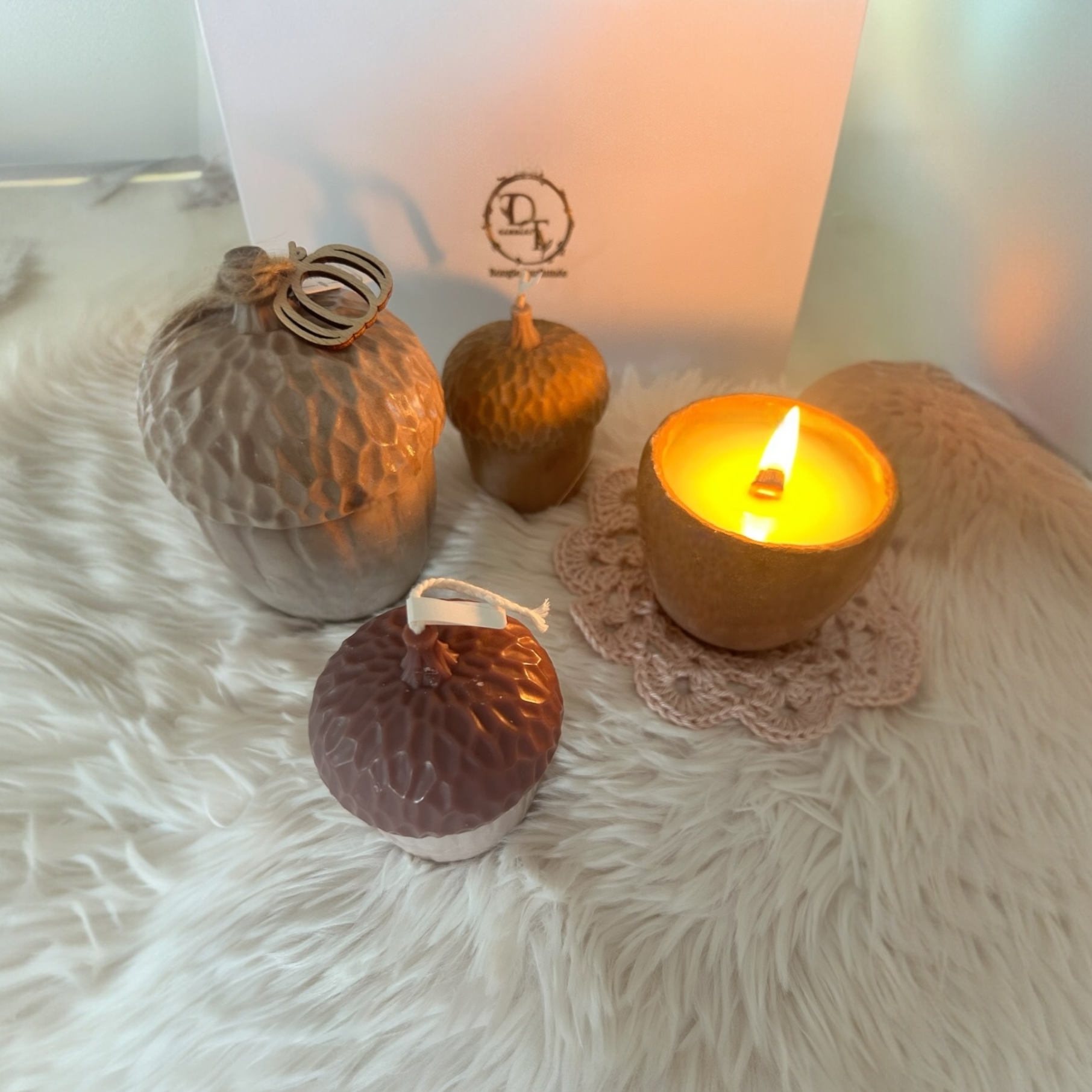 Decorative candles and a lit candle on a fluffy surface with a blurred background