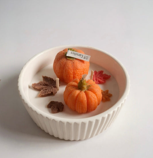 Small pumpkins and leaves in a white bowl on a light gray background