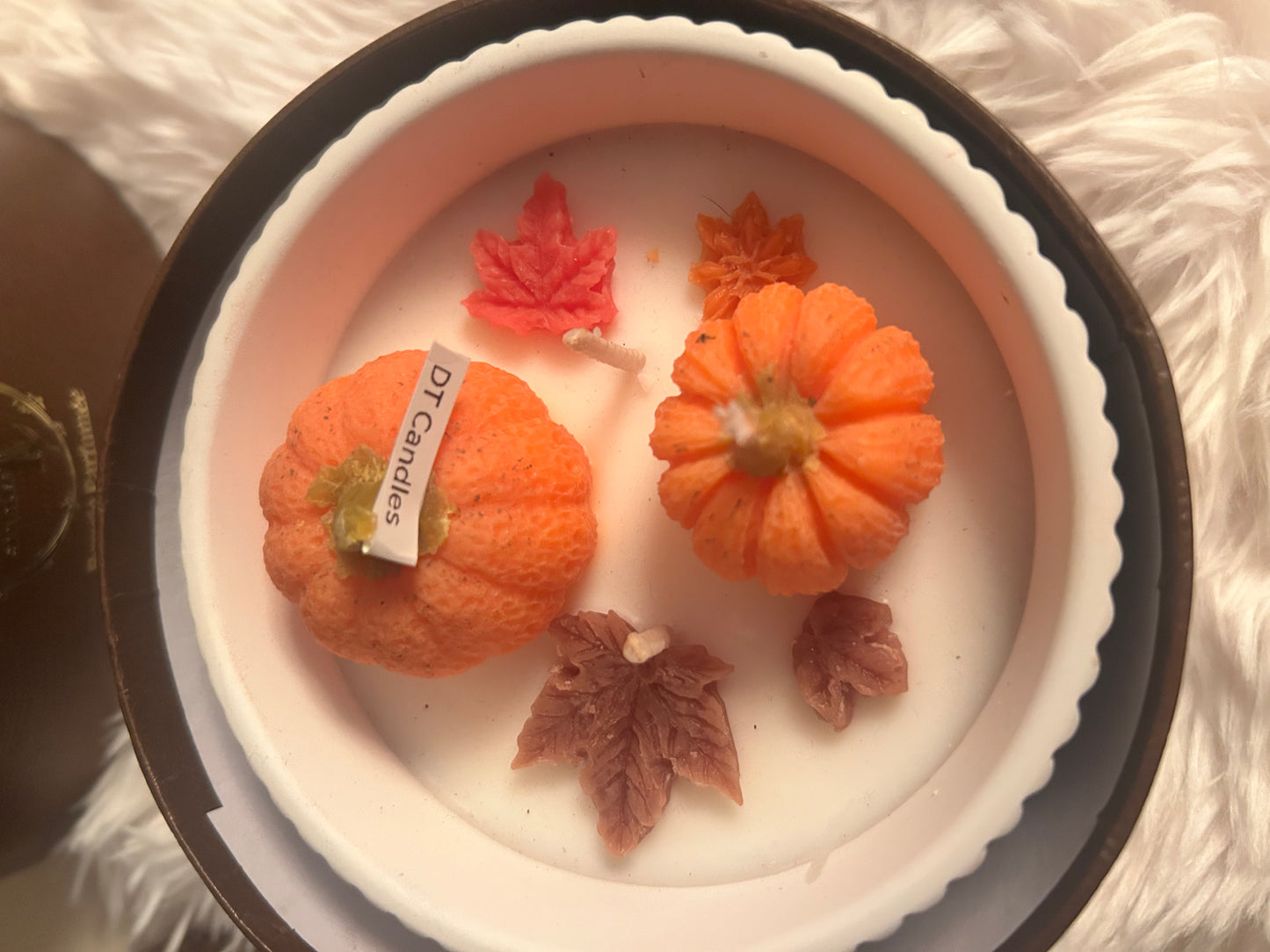 Small pumpkins and leaves on a white plate with 'DR Candles' label.